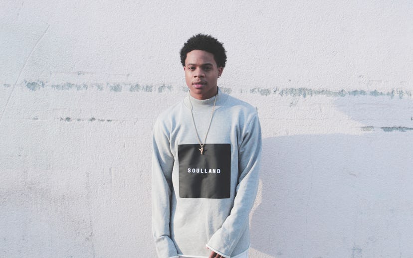 Chris Scholar wearing a grey hoodie with a black square in the middle with "SOULLAND" written inside...