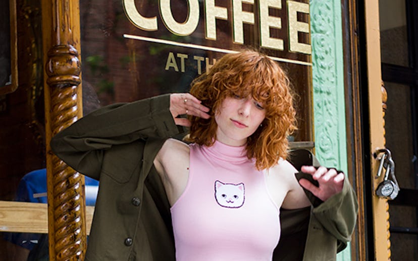 Blogger Claire Geist in a pink cropped turtleneck with a cat on it and a pair of jeans
