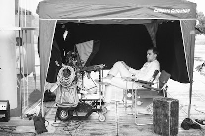 Nicholas Hoult sitting in a tent while looking at shots from the day of filming
