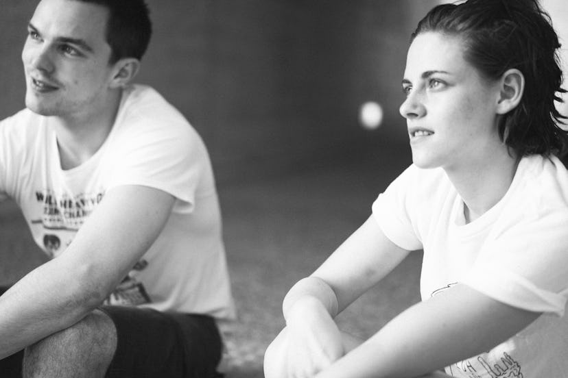 Nicholas Hoult and Kristen Stewart sitting on the ground in white shirts while waiting for filming t...