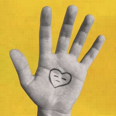 An open hand in front of a yellow background with a heart that is frowning drawn on it