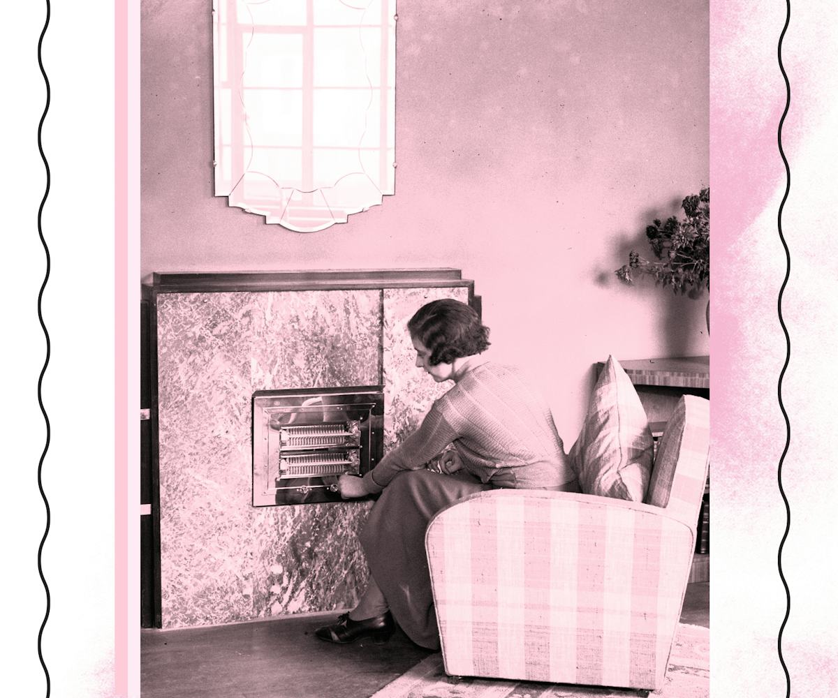 A woman sitting on an armchair next to a fireplace in her living room 