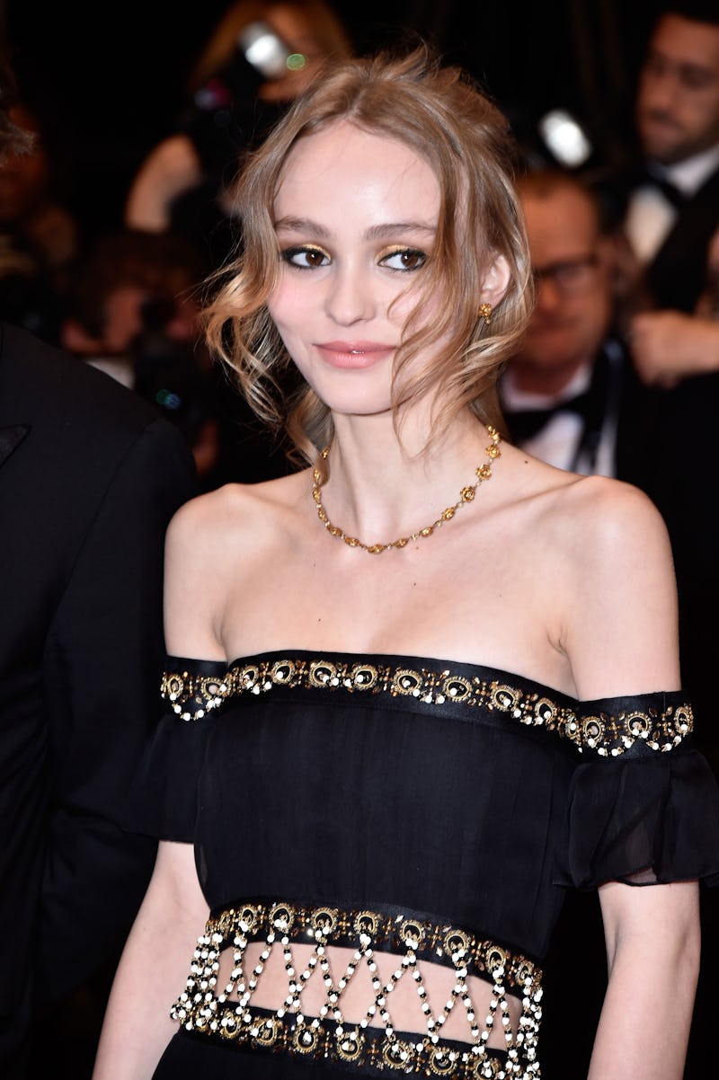 Lilly Rose Depp, famous Channel ambassador, posing in a black dress with gold sequence, with paparaz...