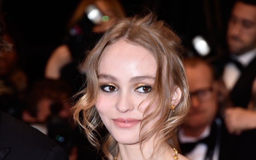 Lilly Rose Depp, famous Channel ambassador, posing in a black dress with gold sequence, with paparaz...