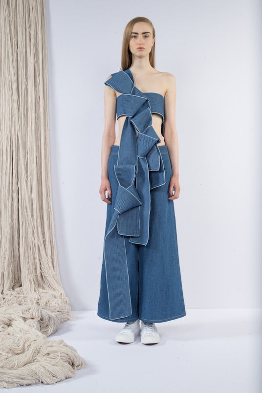A model in a denim top with draped ruffles and denim wide pants by Claudia Li 