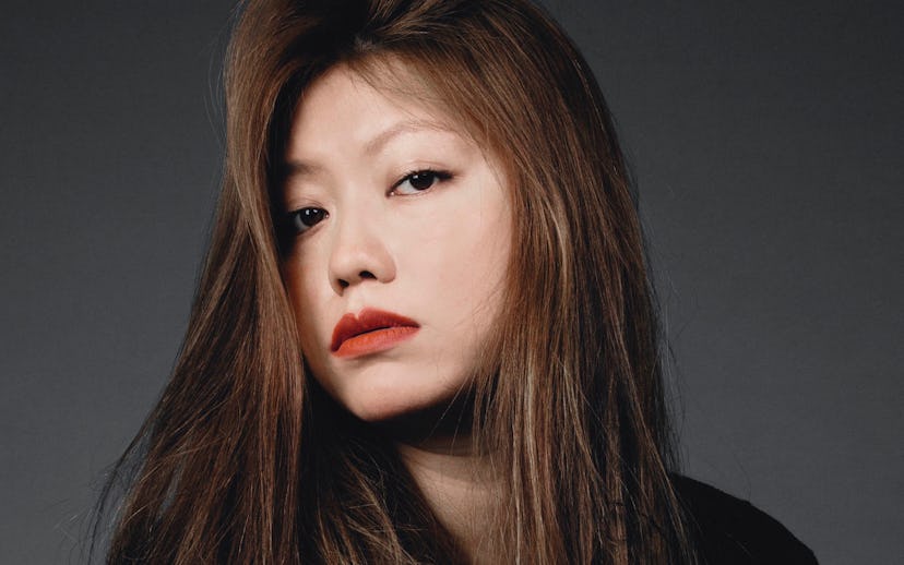 Claudia Li wearing an auburn lipstick shade and a black outfit.