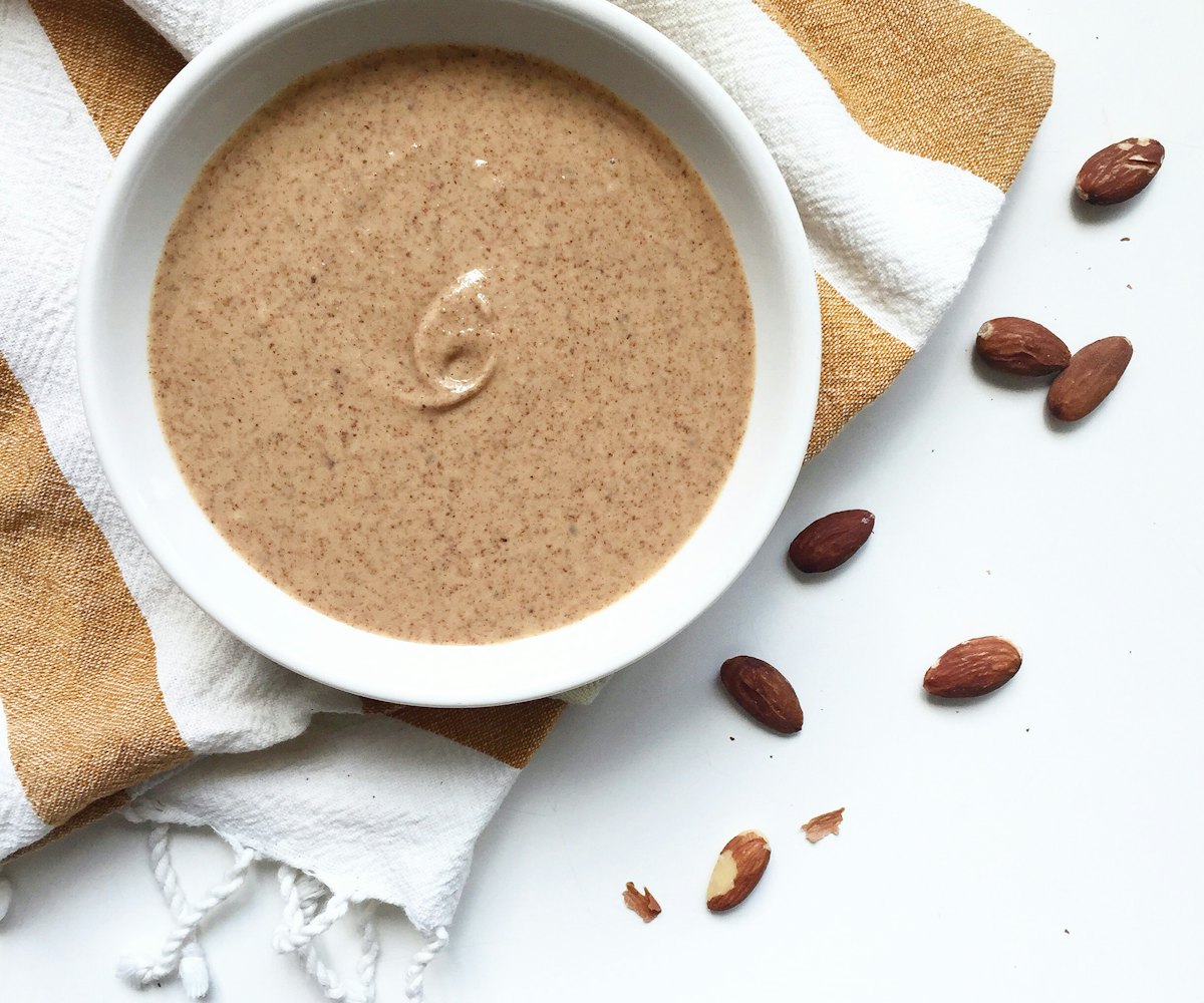 Nut butter in a bowl surrounded by raw nuts