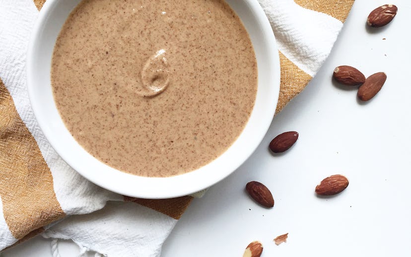 Nut butter in a bowl surrounded by raw nuts