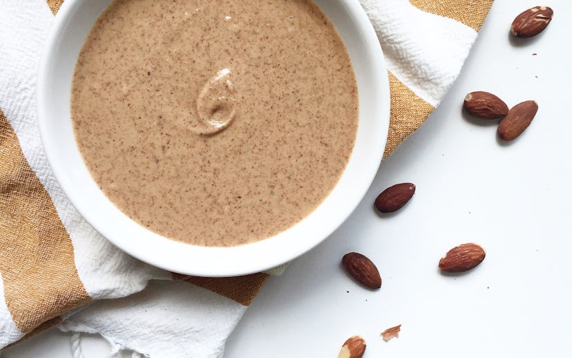 Nut butter in a bowl surrounded by raw nuts