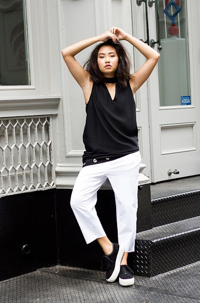 A girl in a black top and white pants.