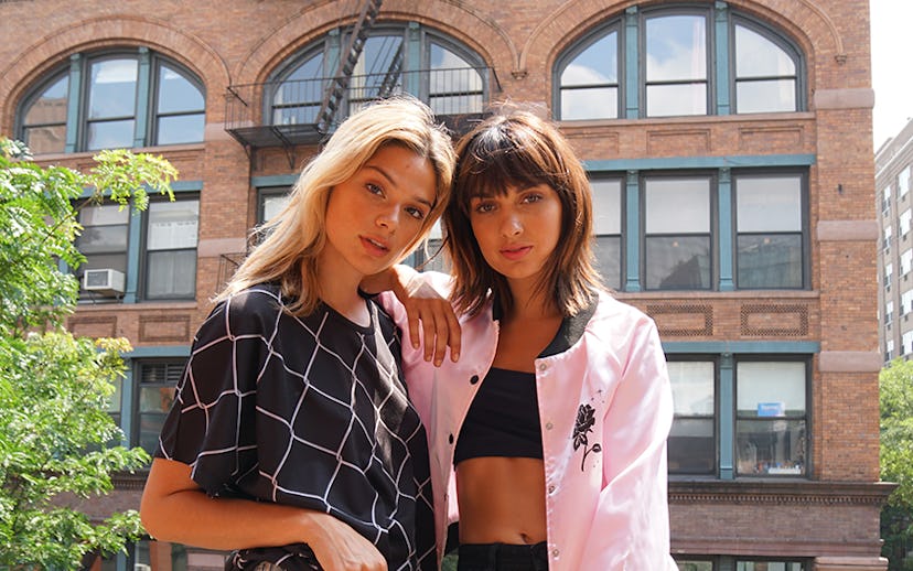 A blonde and a brunette girl hugging each other in outfits from Valley High