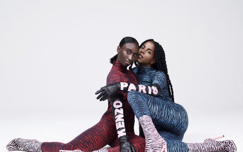 Amy Sall and Juliana Huxtable sitting on the floor next to each other wearing Kenzo striped body sui...