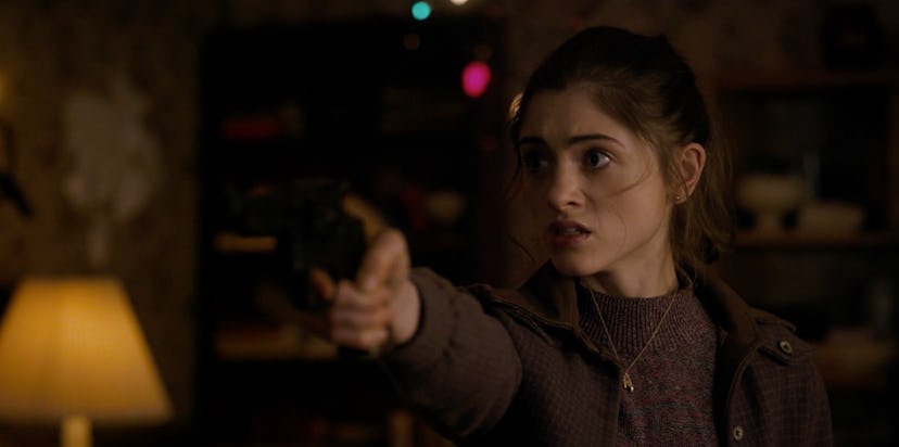 Nancy is pointing the gun toward Steve in the dark living room while having a scared face in the Str...