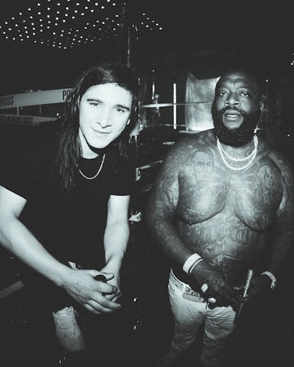 Skrillex in a black shirt with a chain necklace and shirtless Rick Ross with two chain necklaces 