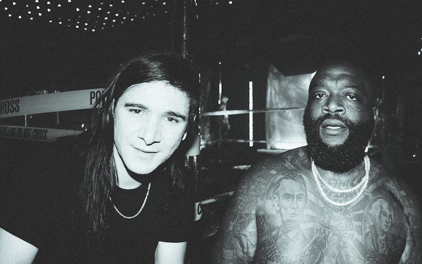 Skrillex in a black shirt with a chain necklace and shirtless Rick Ross with two chain necklaces
