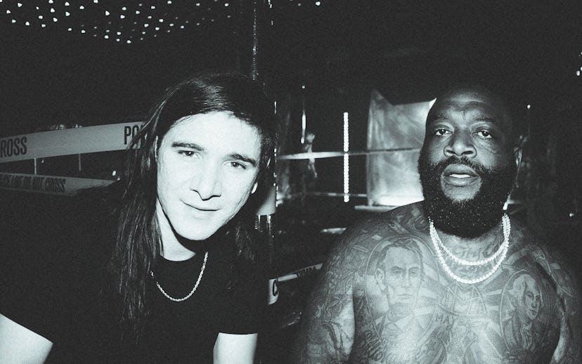 Skrillex in a black shirt with a chain necklace and shirtless Rick Ross with two chain necklaces 