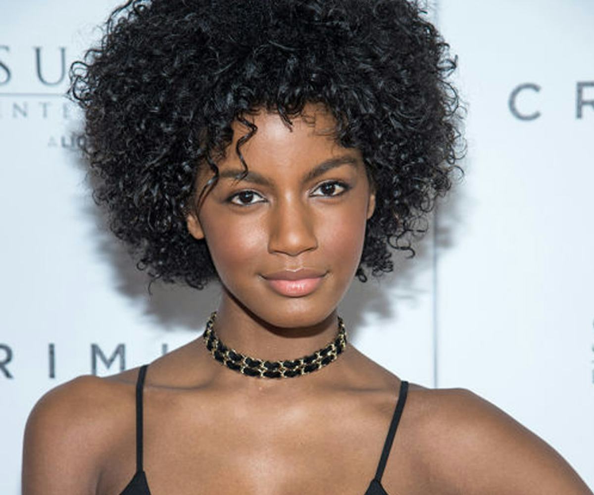 Model Ebonee Davis with a short afro haircut posing in a black dress 