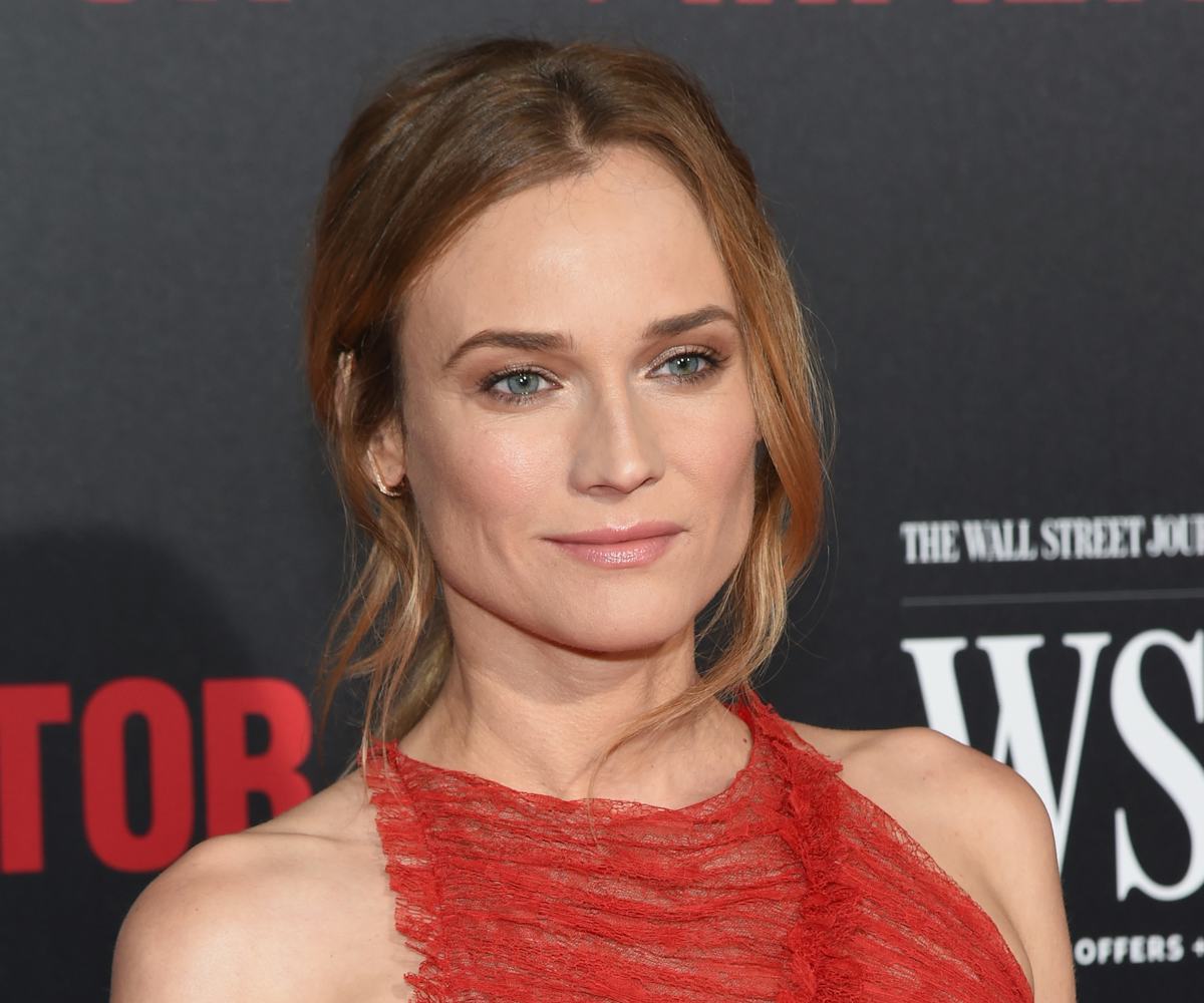 Diane Kruger posing for a photo in a red dress while standing at a red carpet