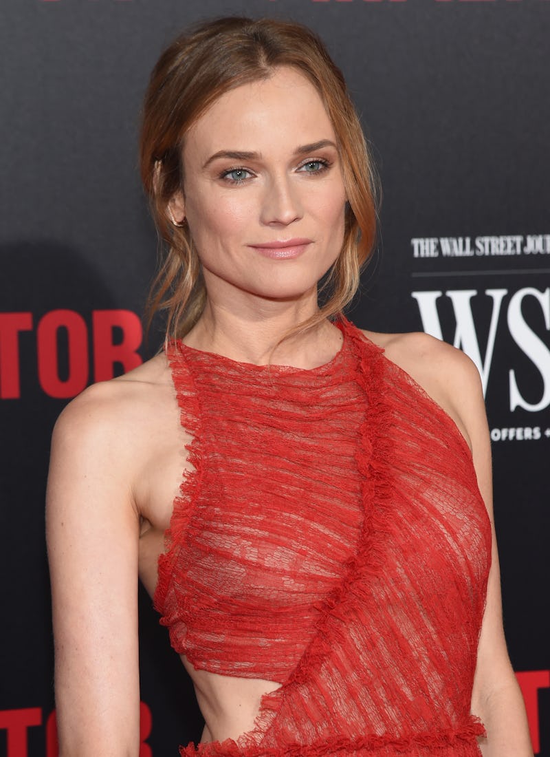 Diane Kruger posing for a photo in a red dress while standing at a red carpet