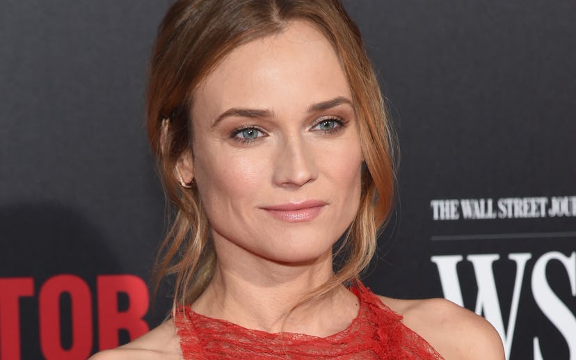 Diane Kruger posing for a photo in a red dress while standing at a red carpet