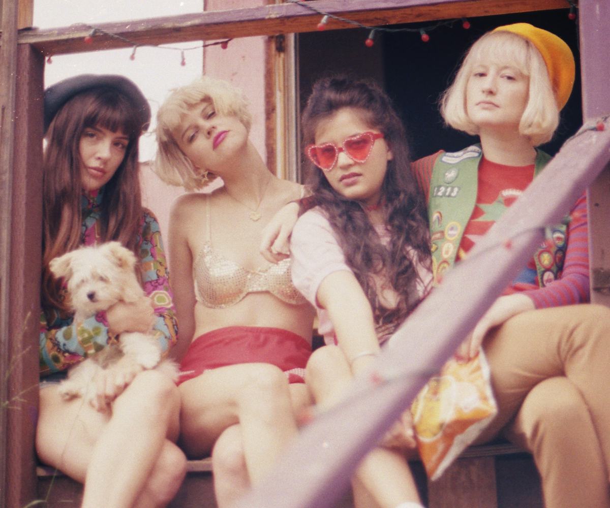 Girl group Ruby the RabbitFoot, sitting on a porch in colorful outfits