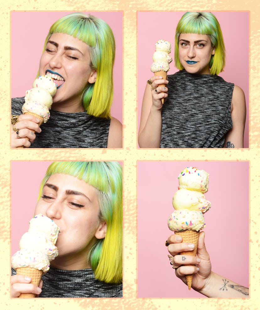 A woman with green hair and green lipstick posing with an ice cream cone and eating it