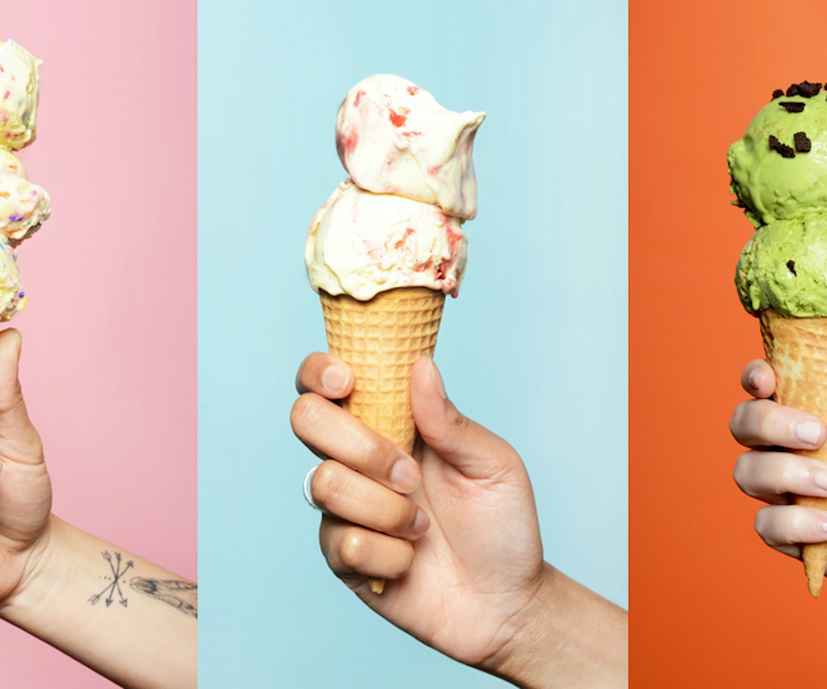 Three hands holding ice cream cones in front of a multicolored background