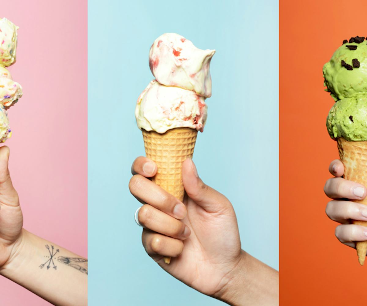 Three hands holding ice cream cones in front of a multicolored background