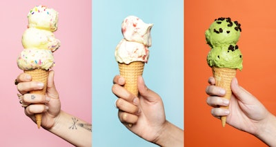 Three hands holding ice cream cones in front of a multicolored background