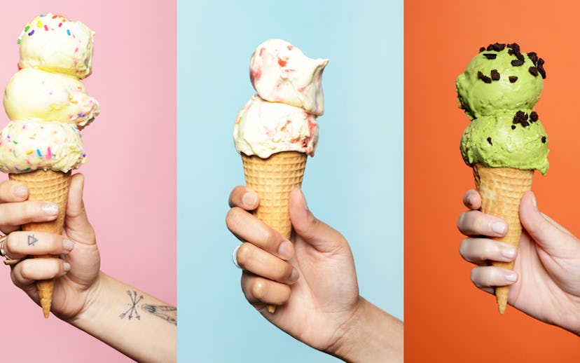 Three hands holding ice cream cones in front of a multicolored background