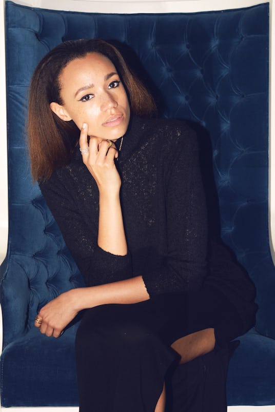 JONES, London-based singer-songwriter in an all black outfit sitting on a blue chair