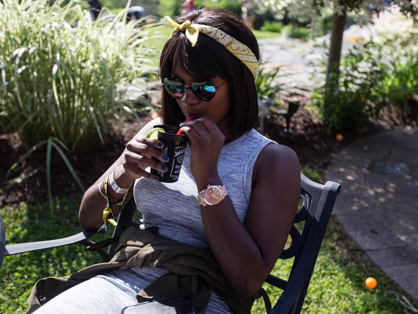 A girl sitting and drinking from a Jack Daniels cup