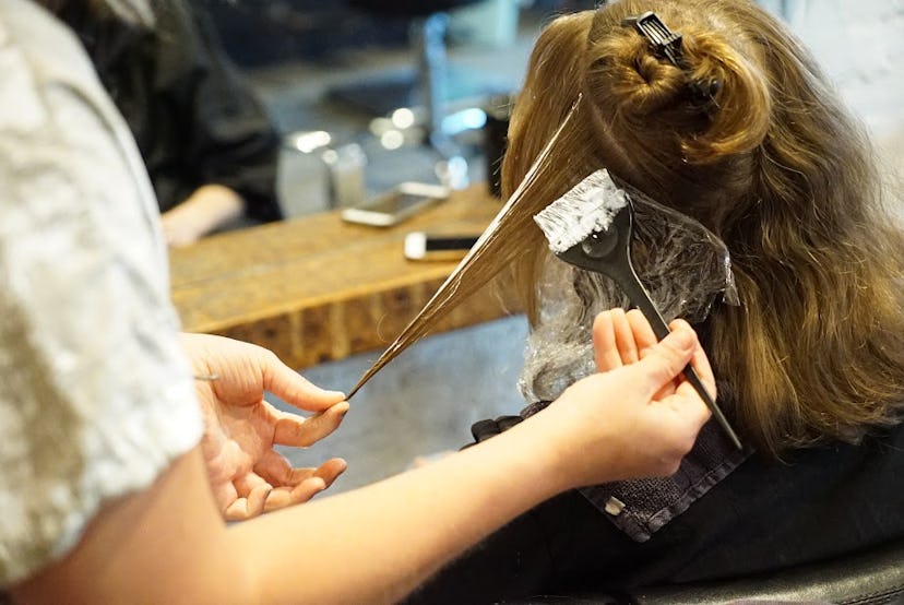 A woman at the salon dyeing her hair blonde but keeping her natural root 