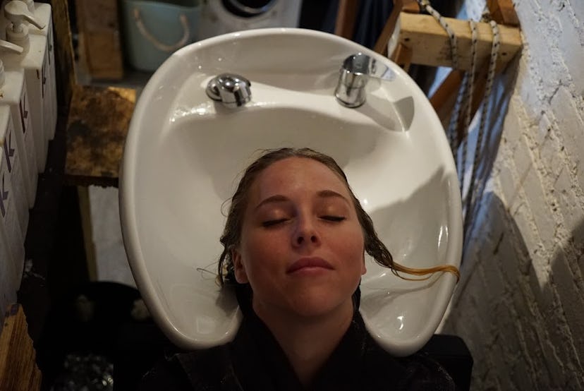 A woman at the salon with her hair in the sink, getting a tone 