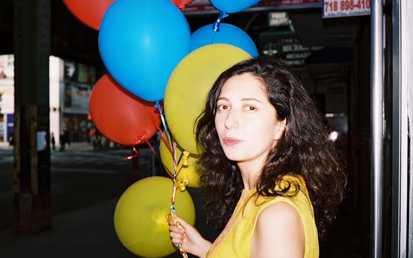 Maria Usbeck wearing a yellow sleeveless top while holding three yellow, two blue, and two red ballo...