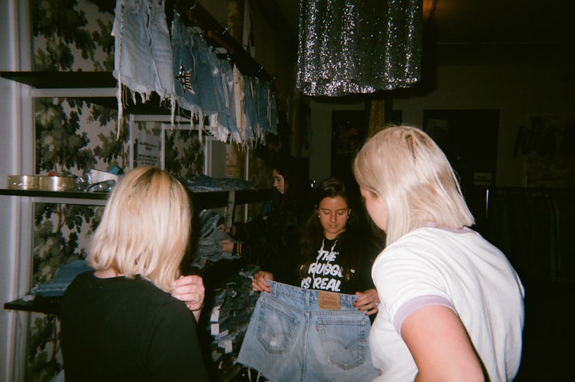 Two blonde women looking at a pair of cutoff shorts