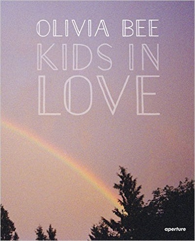 Cover of female photographer Olivia Bee's book 'Kids in Love,' with a rainbow in the sky background.