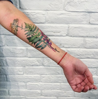 Green fern tattoo on a left hand