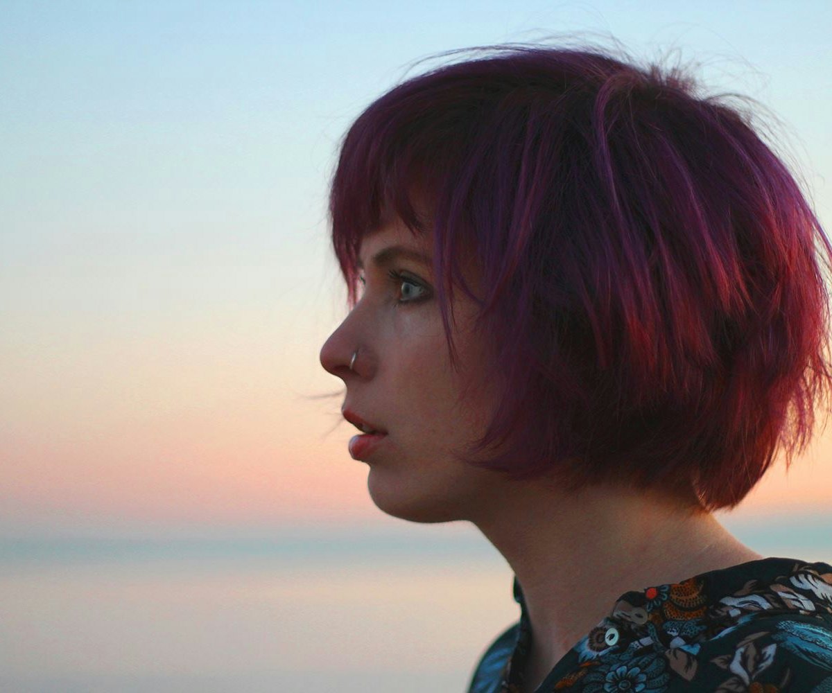 A side profile view of Jazz Morley wearing a black floral shirt and blue-pink sky in the background