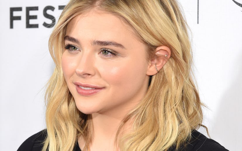 Chloë Grace Moretz posing while wearing a black shirt and two small ear cuffs on her left ear