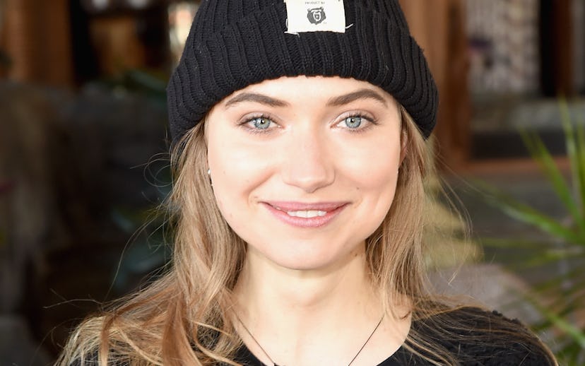 Imogen Poots in a black wool cap and a sweater smiling at the camera