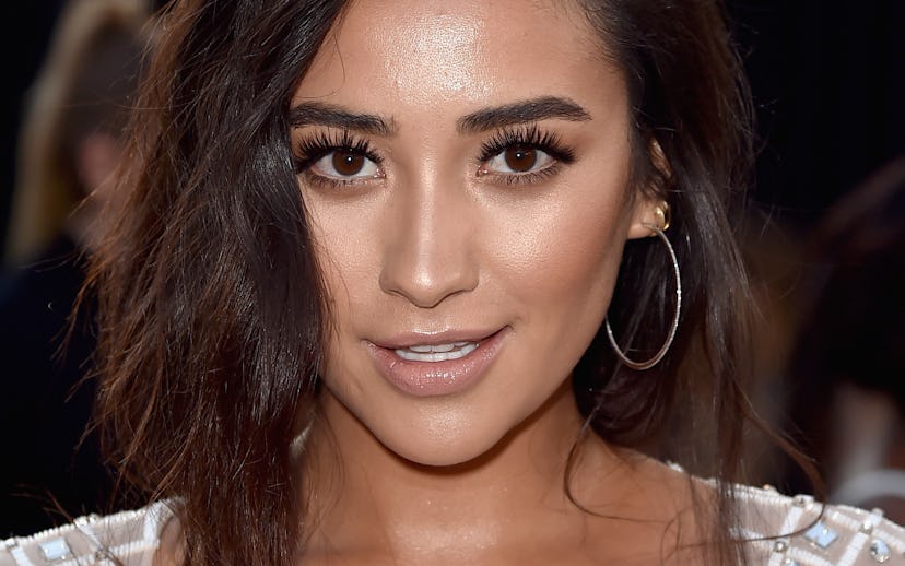 Shay Mitchell wearing glowy nude makeup with voluminous lashes and a sheer white top with mirror gem...