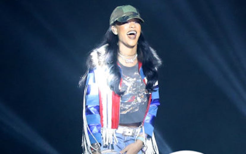 Rihanna wearing a blue jacket with a faux-fur collar, red and white scarf, blue denim jeans, and a w...