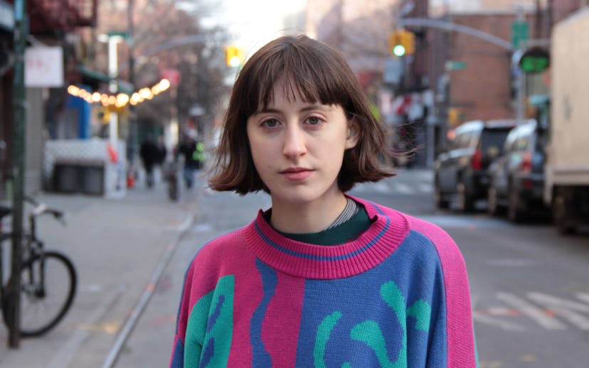 Frankie Cosmos (Greta Kline) standing at a street while wearing a sweater with pink, blue, and green...