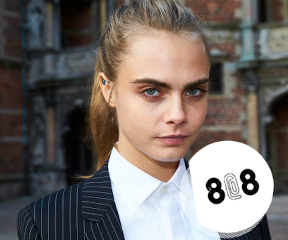 Cara Delevingne posing in a white button-up and black striped blazer