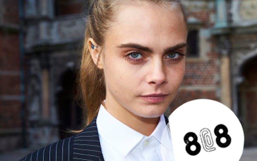 Cara Delevingne posing in a white button-up and black striped blazer