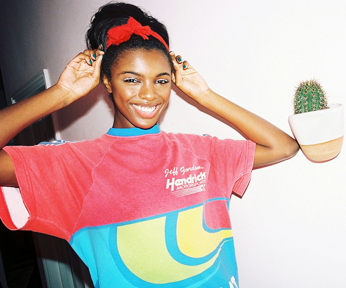 Leomie Anderson in a red T-shirt with a blue collar and a red headband with a bow, smiling 