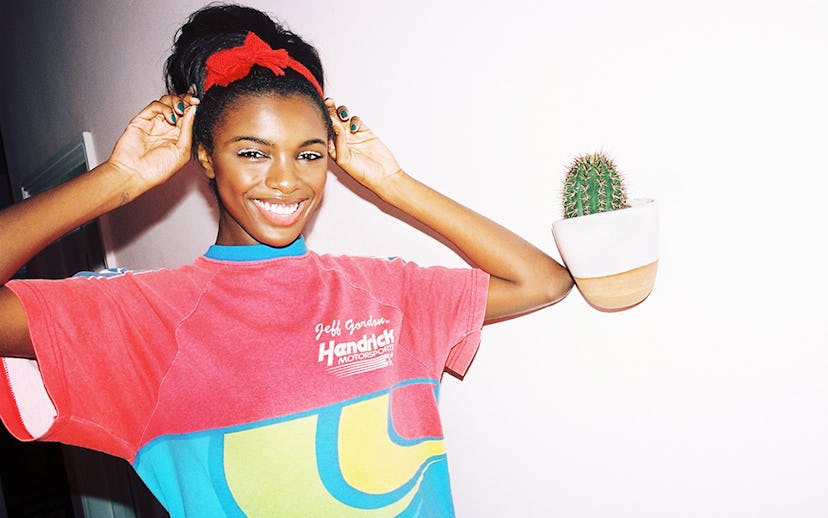 Leomie Anderson in a red T-shirt with a blue collar and a red headband with a bow, smiling