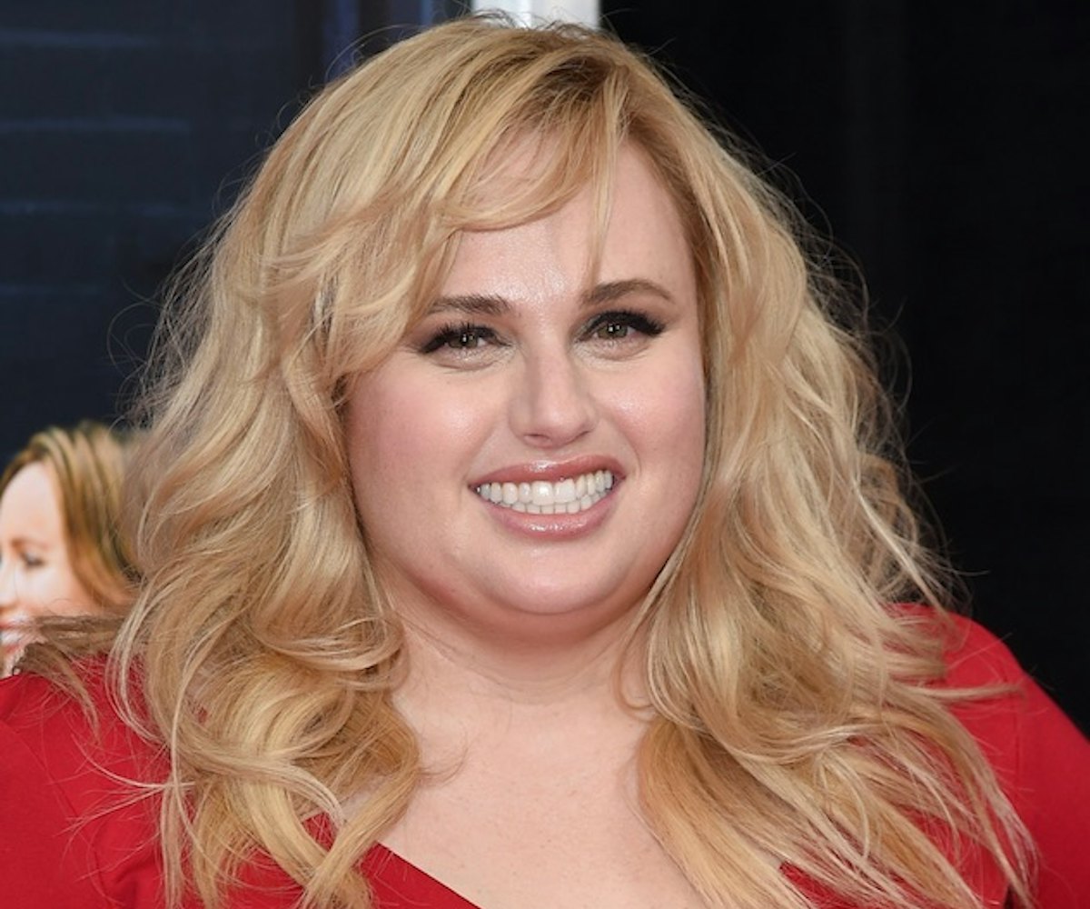 Rebel Wilson in a red dress with shiny details talking about being singe and female-driven comedies.