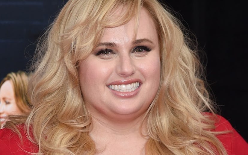 Rebel Wilson in a red dress with shiny details talking about being singe and female-driven comedies.